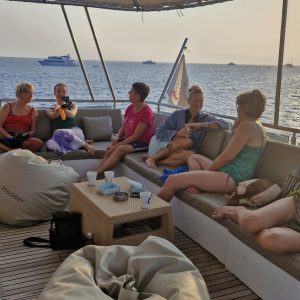 fünf Frauen sitzen auf dem Deck eines Schiffes und unterhalten sich