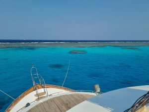 Blick von einem Schiff auf azurblaues Wasser und ein Riff