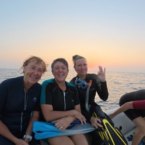 Drei Frauen sitzen auf einem Boot und lachen in die Kamera