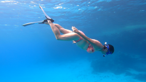Frau schnorchelt und taucht unter die Wasseroberfläche